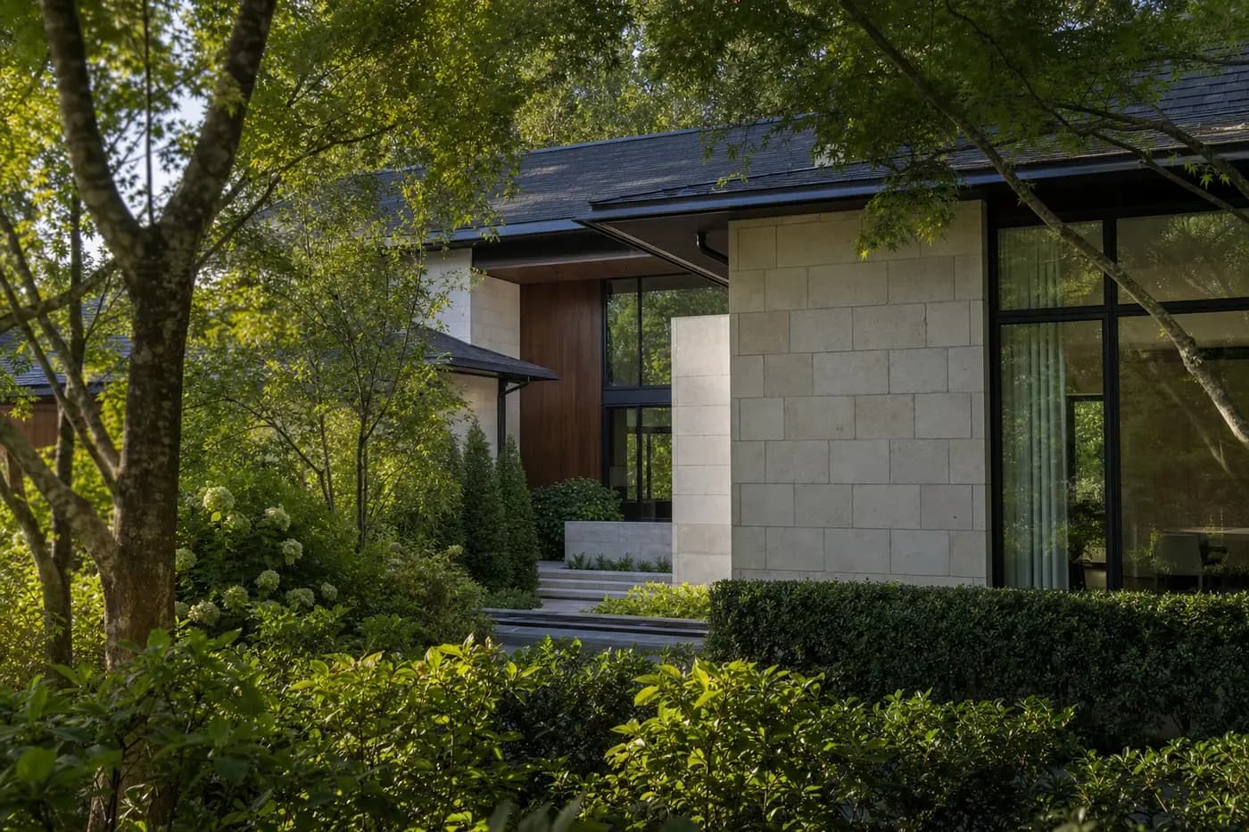 Luxury Charlotte custom home screened by layered trees and garden walls around a private entry court