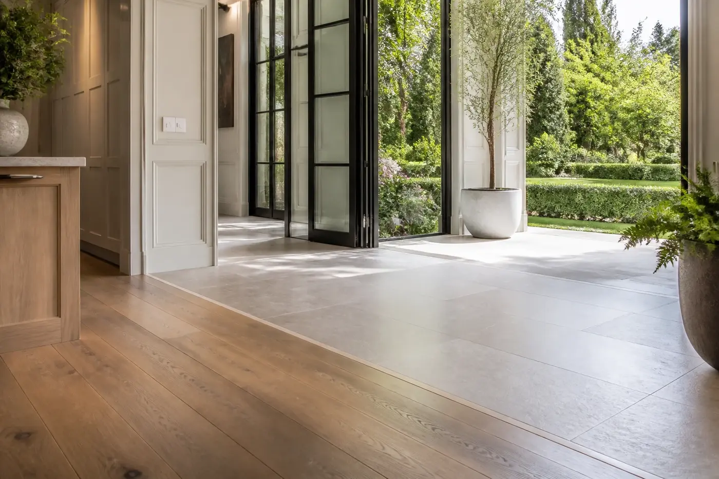 Flush transition from wide-plank white oak to large-format limestone at a new custom-home garden-room threshold