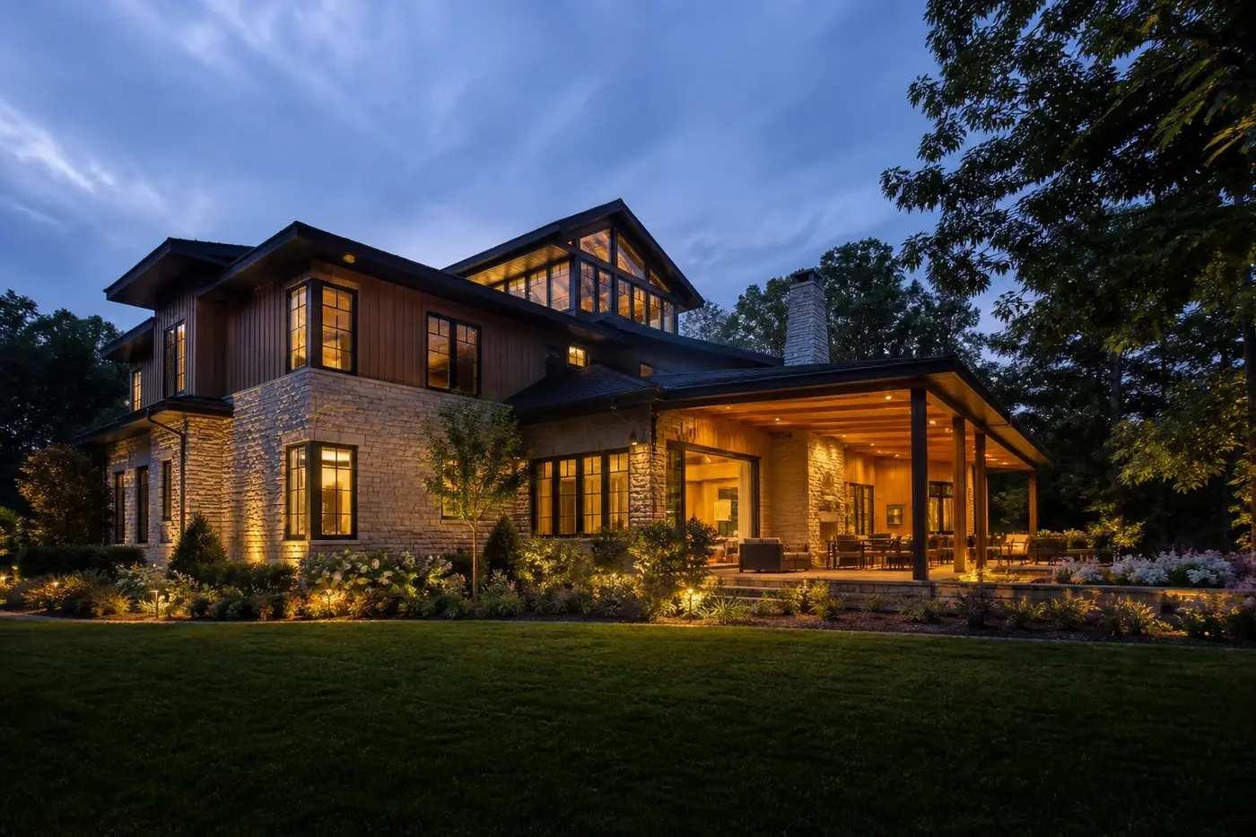 New Charlotte luxury custom home with warm architectural lighting across the garden facade and covered outdoor room