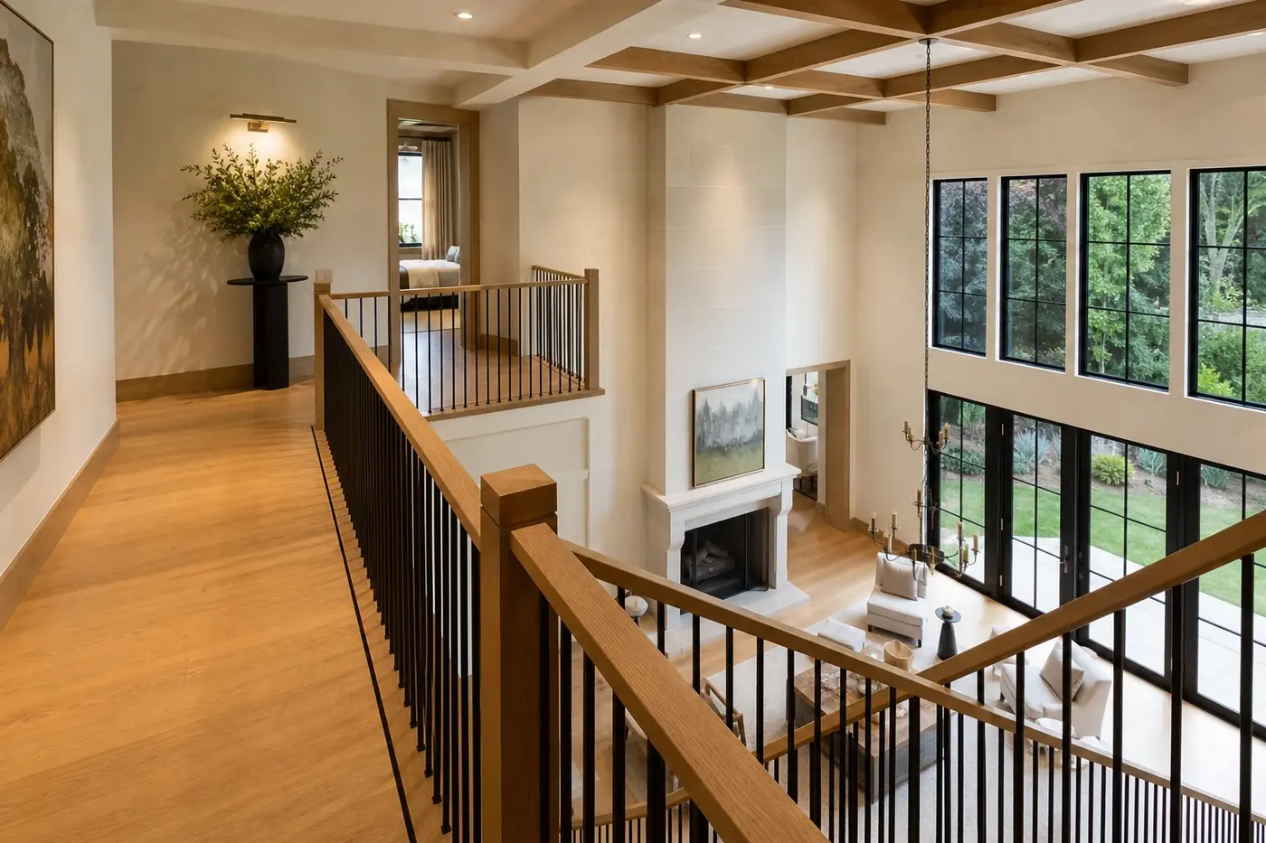 Upper gallery in a luxury custom home with a continuous oak-capped dark metal guard overlooking the great room