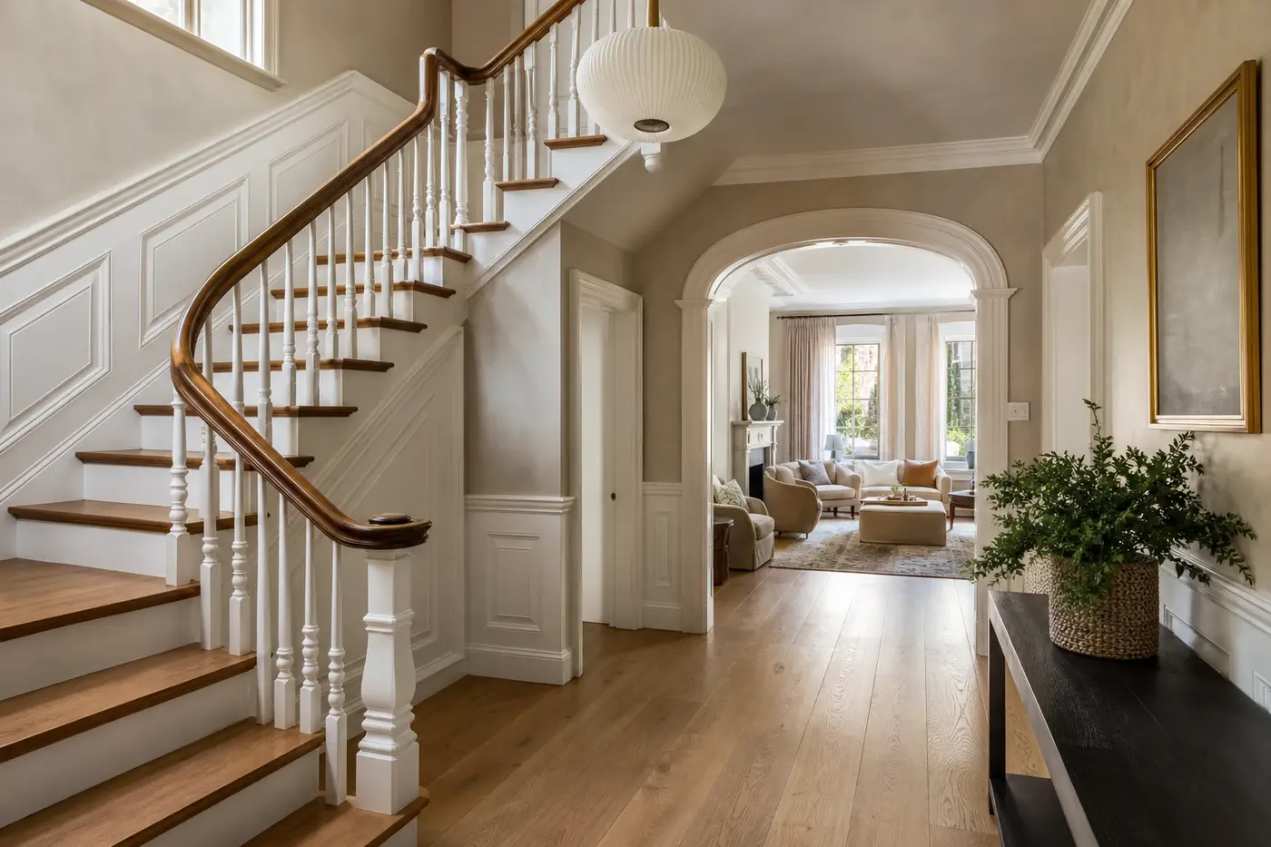 Restored wood staircase and paneled entry hall opening into a refined renovated living room