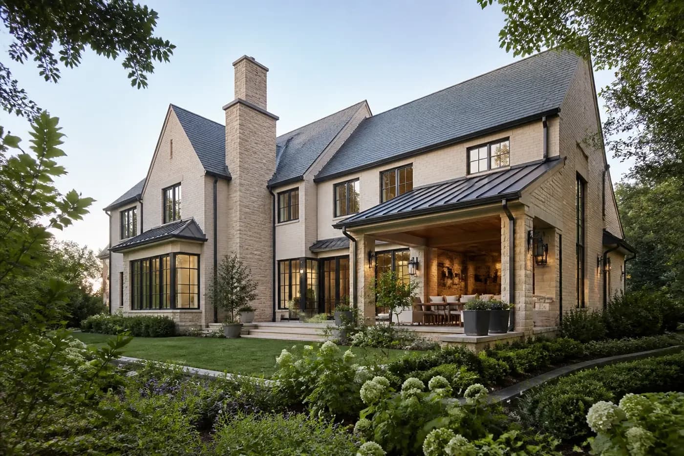 Completed Charlotte luxury custom home with limestone, brick, black-framed windows, and a landscaped garden