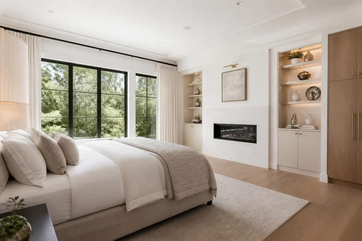 New Charlotte luxury custom-home guest suite with a garden view, white oak millwork, warm neutral finishes, and a limestone fireplace wall